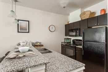 a kitchen with granite counter tops and black appliances at 310 at Nulu Apartments-Student, Louisville, KY
